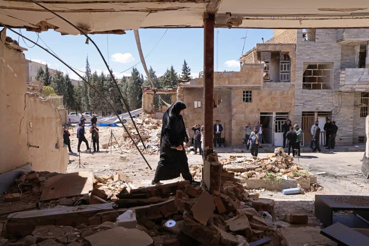 زنی در حال عبور از کنار ساختمانهای مسکونی آسیبدیده در حملات اخیر به شهرک وحدت در کرج، جنوب غربی تهران، در تاریخ ۳ آوریل ۲۰۲۶.