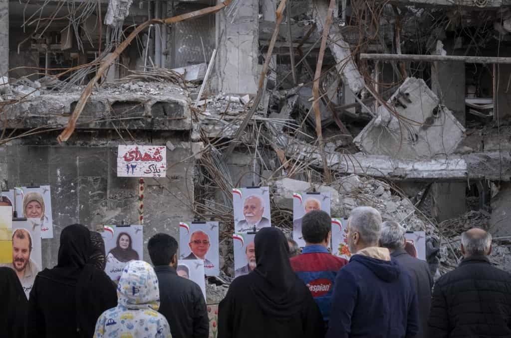 مردم در مقابل پرترههای ساکنان متوفی که بر روی ویرانههای ساختمانی در یک منطقه مسکونی