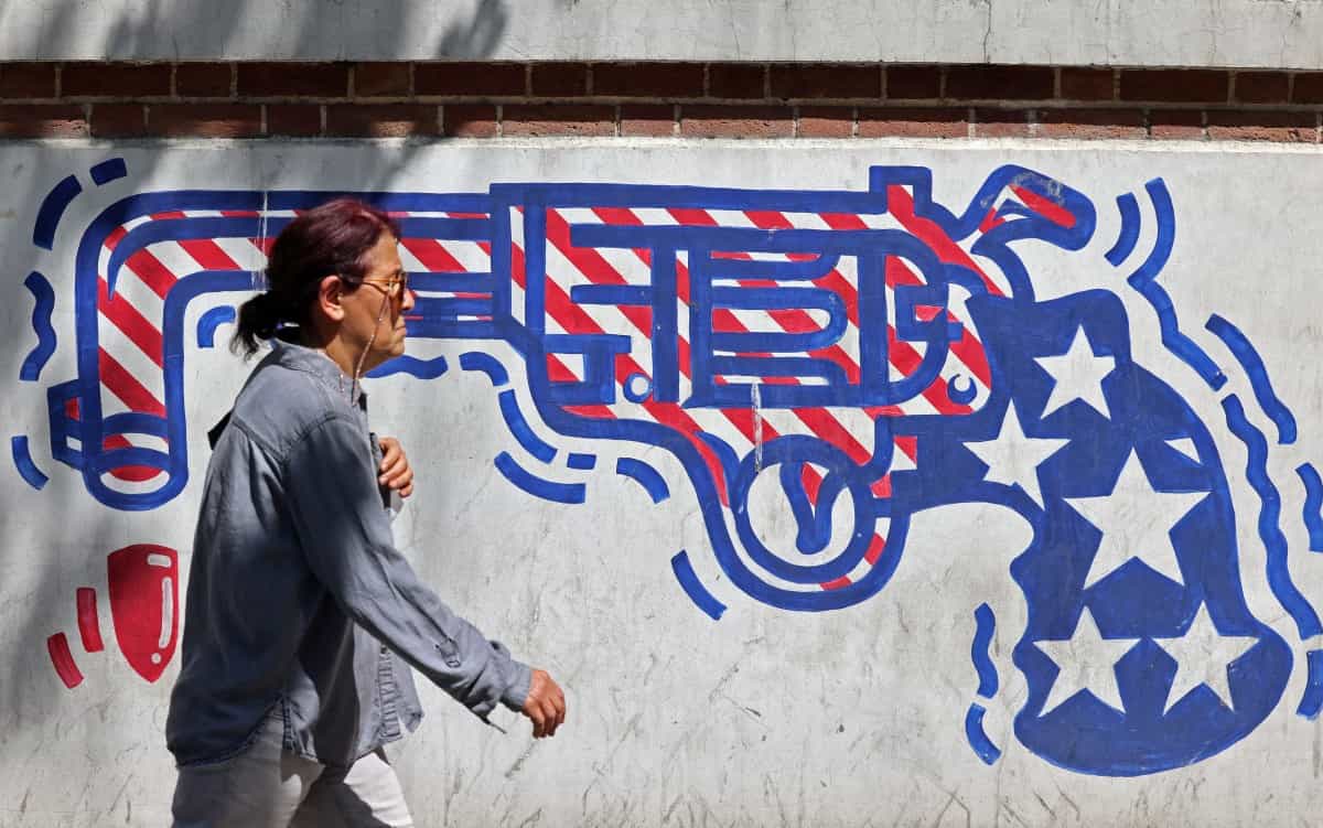 زنی در حال عبور از کنار یک نقاشی دیواری ضد آمریکایی در نزدیکی سفارت سابق آمریکا