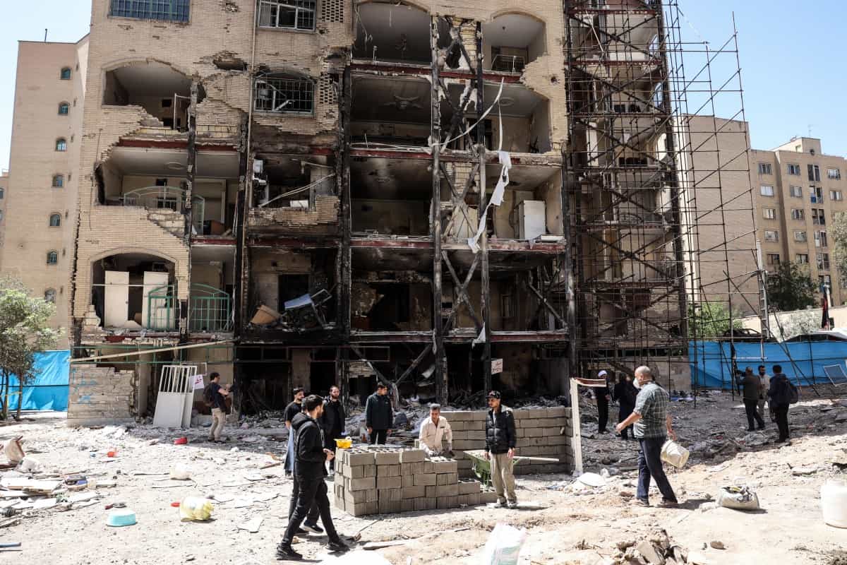 کارگران و روزنامه‌نگاران در مقابل یک ساختمان مسکونی که چند روز قبل از اجرای آتش‌بس دو هفته‌ای بین ایران و ایالات متحده، مورد حمله هوایی ایالات متحده و اسرائیل قرار گرفت، در مجتمع مسکونی شهید بروجردی در جنوب تهران در ۱۴ آوریل ۲۰۲۶ ایستاده‌اند.