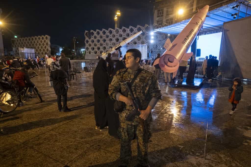 یک پسر ۱۶ ساله با لباس نظامی سپاه پاسداران انقلاب اسلامی (IRGC) در حالی که یک تفنگ AK-45 در دست دارد، در طول یک راهپیمایی طرفدار دولت در جنوب تهران، ایران، در تاریخ ۱۹ آوریل ۲۰۲۶، منطقه‌ای را زیر نظر دارد.