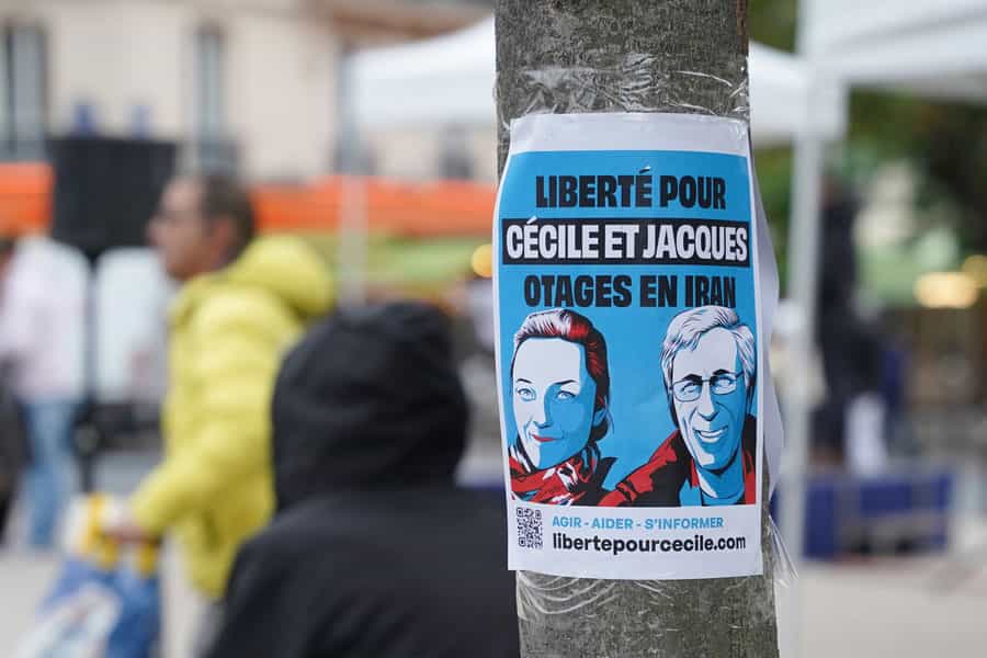 پلاکاردی با تصاویری از سسیل کولر و ژاک پاریس به روی ستونی چسبیده شده است.