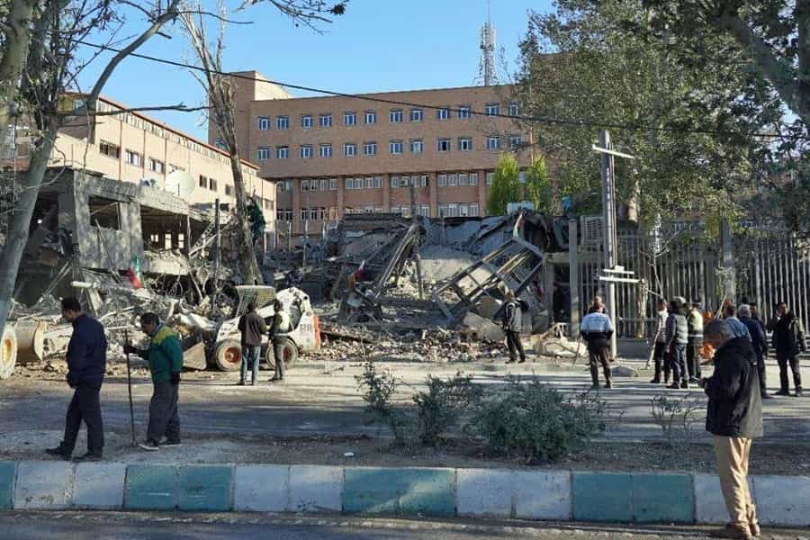 در تصویر، بخشی از ساختمان دانشگاه صنعتی شریف تهران که ویران شده است دیده میشود. در اطراف آن عدهای حضور دارند.