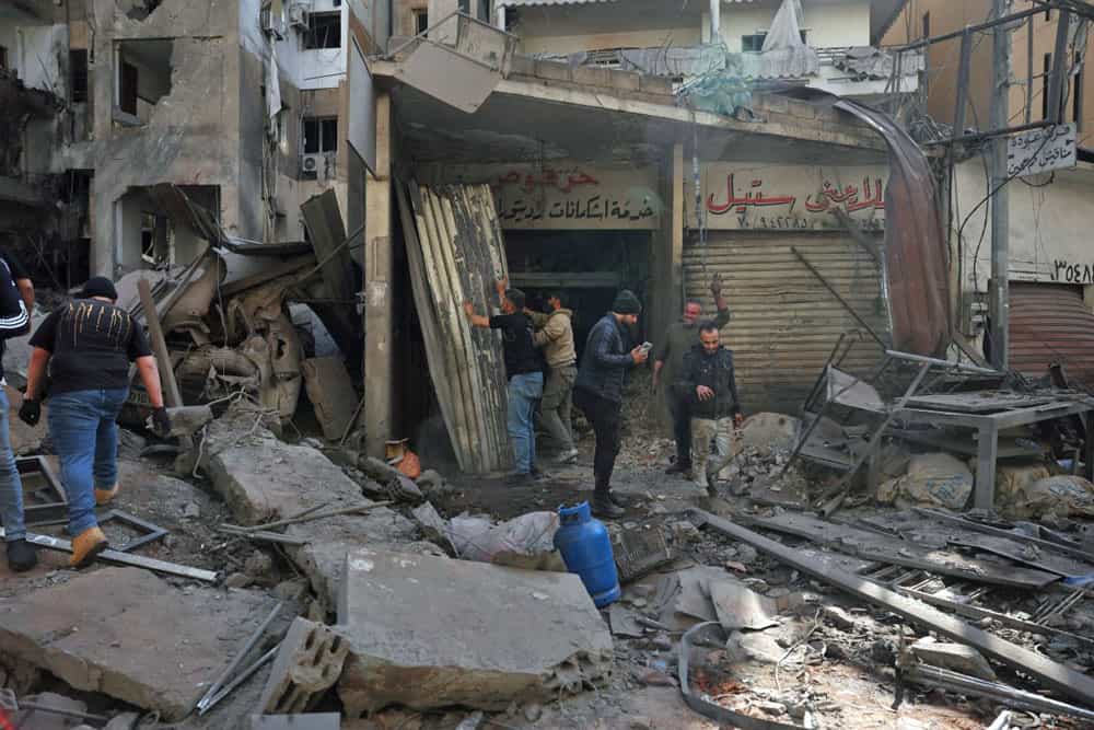مردم پس از حمله هوایی اسرائیل به منطقه شیاح در حومه جنوبی بیروت در حال کمک در میان آوار جلوی یک مغازه هستند.