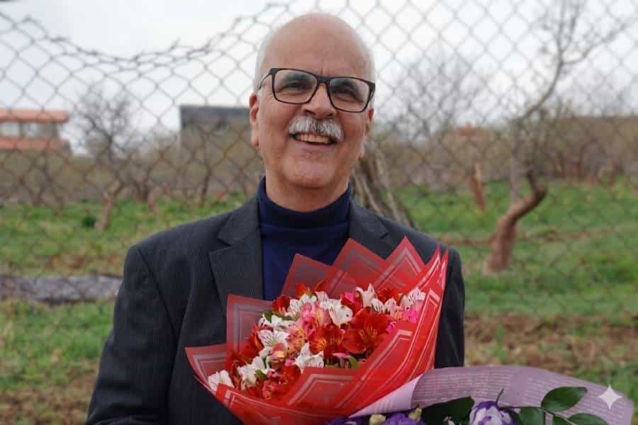 سعید مدنی در حالی‌که دسته‌گلی در دست دارد رو به دوربین می‌خندد.