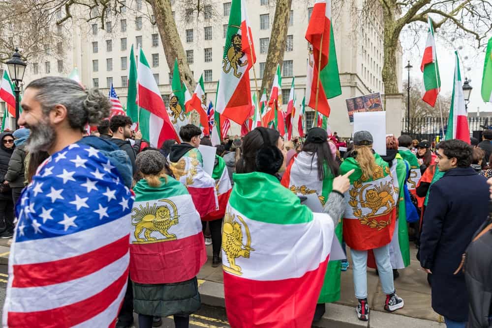 معترضان پرچم ایران، پرچم شیر و خورشید اسرائیل و پرچم ایالات متحده را در دست دارند.