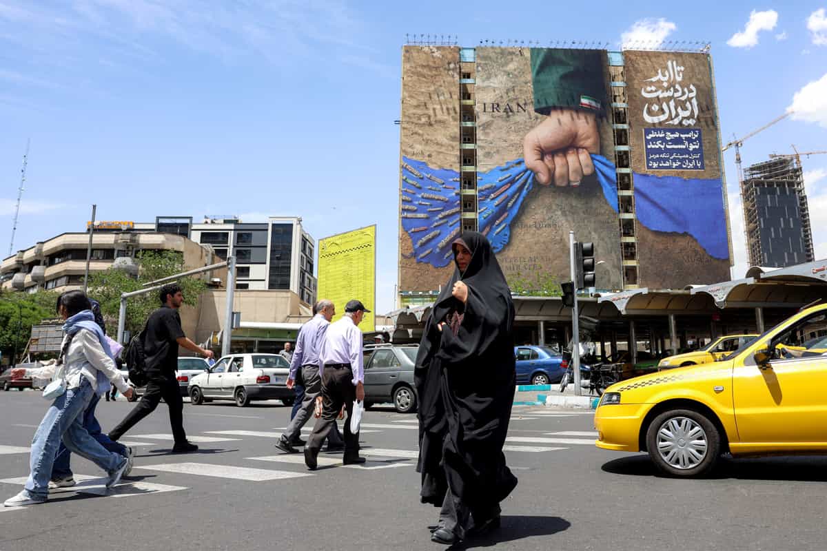 زن جوانی از خیابان عبور می‌کند که در نزدیکی بیلبوردی روی نمای یک ساختمان در میدان ونک تهران قرار دارد. این بیلبورد تنگه هرمز را نشان می‌دهد و بر روی آن نوشته شده: «همیشه در دست ایران». (عکس: خبرگزاری فرانسه)