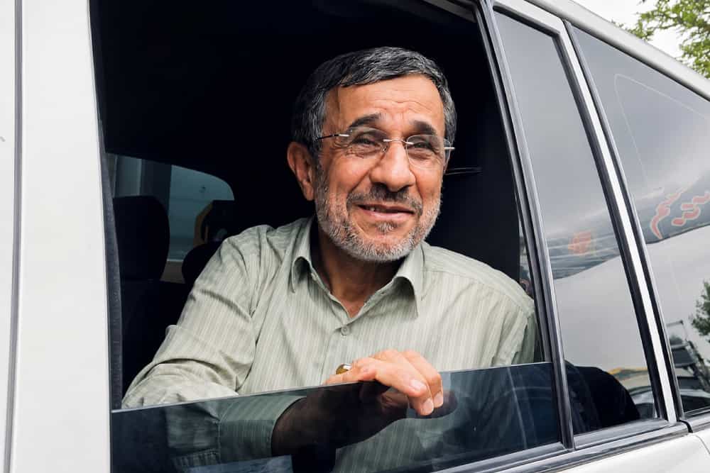 در این تصویر محمود احمدینژاد سر خود را از پنجره خودرو بیرون آورده و دارد میخندد.