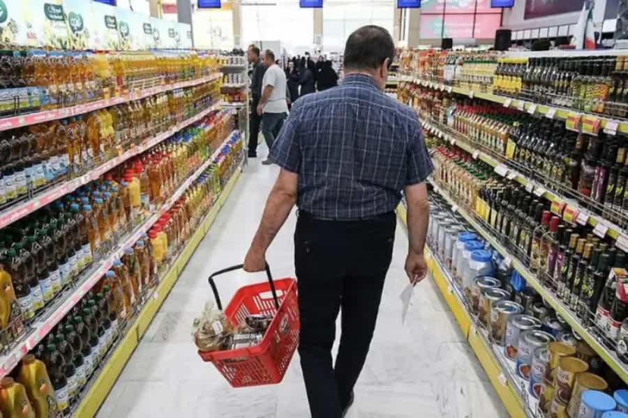 مردی در میان قفسه های خرید یک فروشگاه دیده می شود.