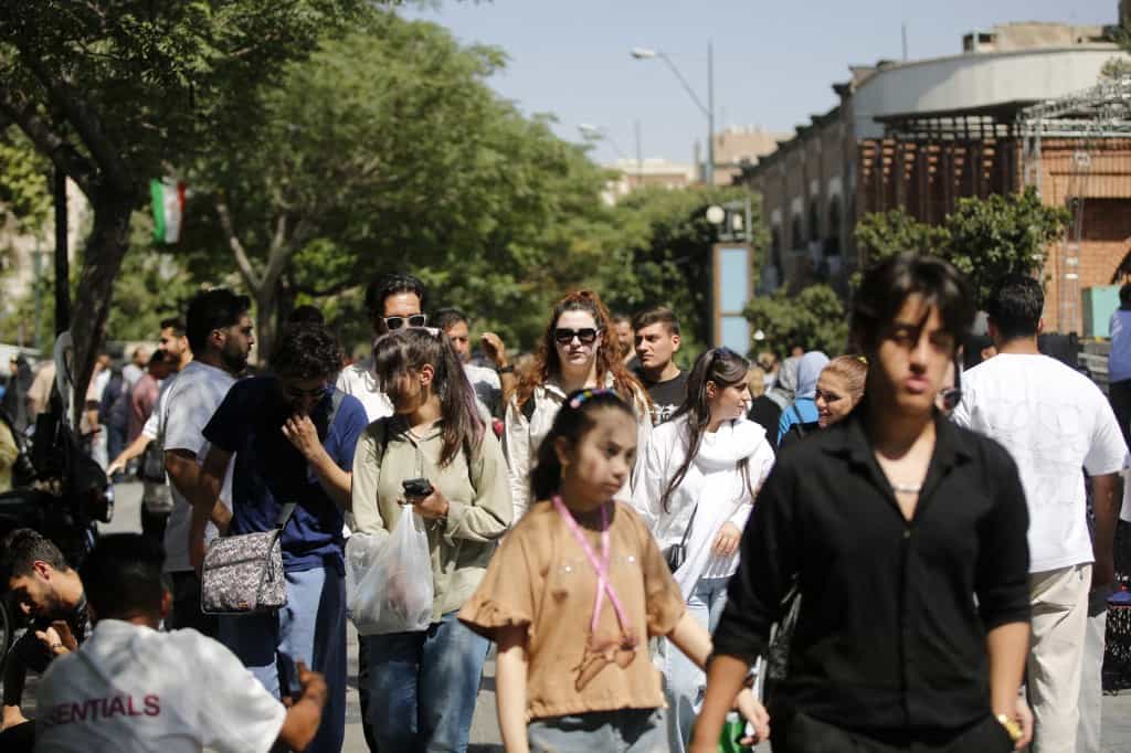 در تصویر زنان و مردان جوان در خیابان دیده میشوند.