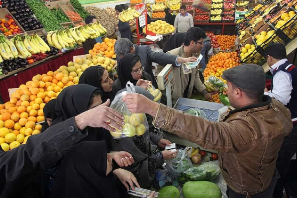 تصویری از یک میوه‌فروشی که در آن فروشندگان در حال حساب کردن خرید مشتریان هستند.