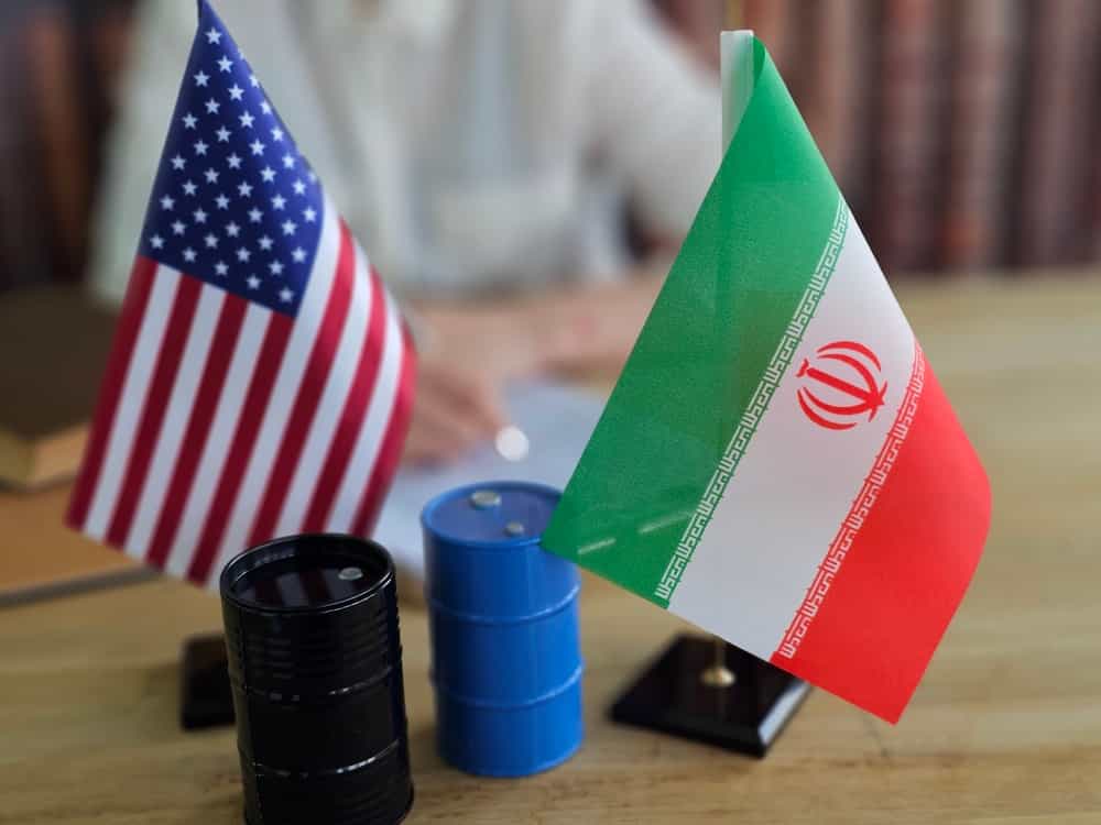 بحث در مورد تجارت نفت بین ایالات متحده و ایران با پرچمها و بشکههای حاضر در یک میز
