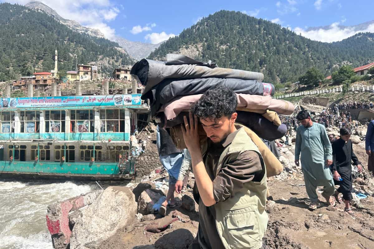 مردی پس از سیل ناگهانی در شهر پارون، مرکز ولایت نورستان افغانستان، وسایل زندگی خود را نجات میدهد