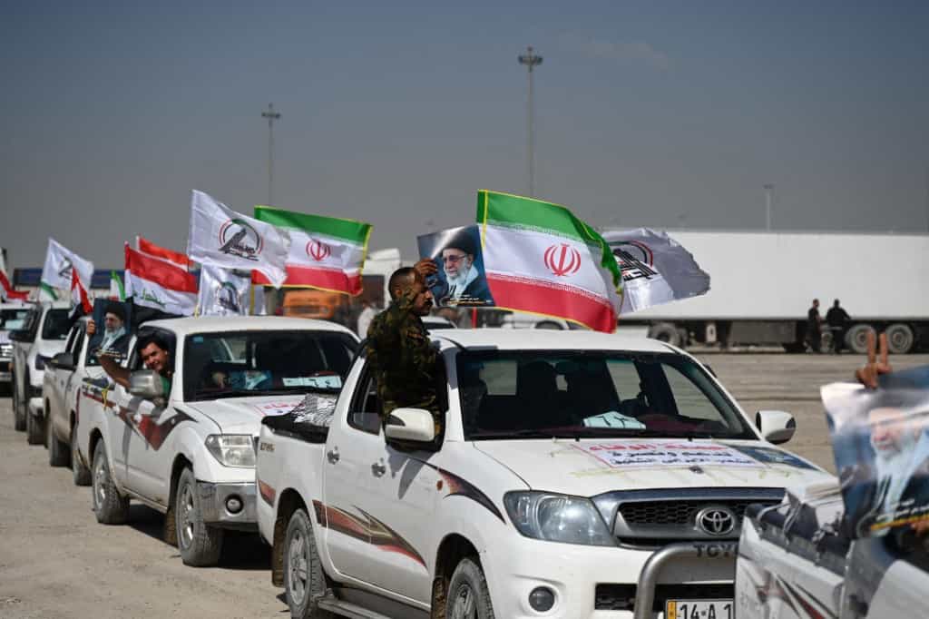 در تصویر کاروان خودروهای حشد الشعبی با تصاویر علی خامنه‌ای، رهبر کشته شده جمهوری اسلامی و پرچم‌های ایران و حشد الشعبی دیده می‌شود.