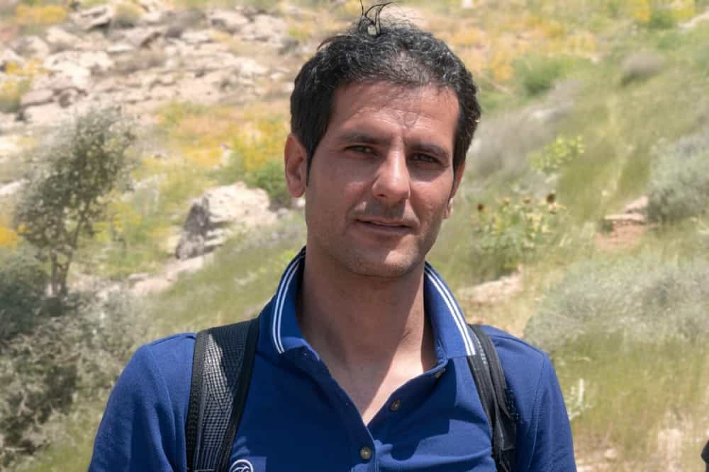 تصویری از چهره سعید حسنی در میان طبیعت با کولهپشتیای بر پشت..