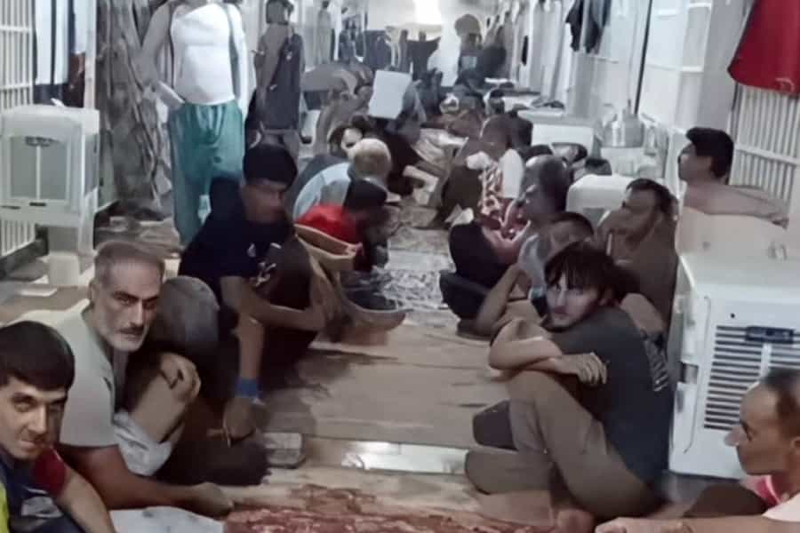 تصویری از زندانیان واحد ۲ زندان قزلحصار در کریدور بند که در کنار هم نشسته‌اند.