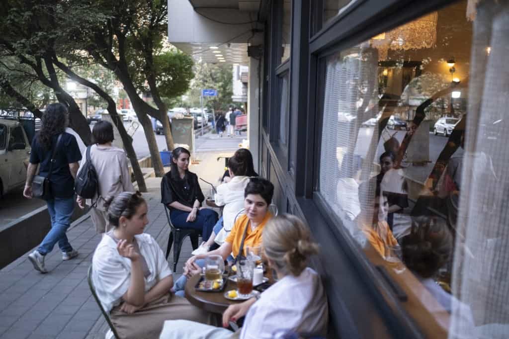 جوانان ایرانی در تاریخ ۱۲ ژوئن ۲۰۲۶، درست در خارج از کافهای در مرکز تهران، ایران، در کنار یکدیگر نشستهاند.