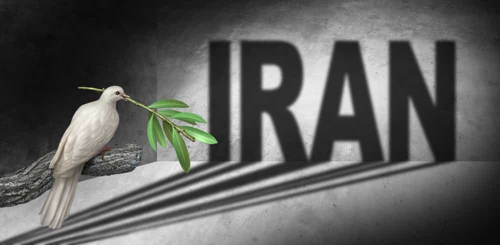 کبوتر صلح با شاخه زیتون بر نوک، نظاره‌گر دیواری است که بر آن به انگلیسی نوشته شده ایران