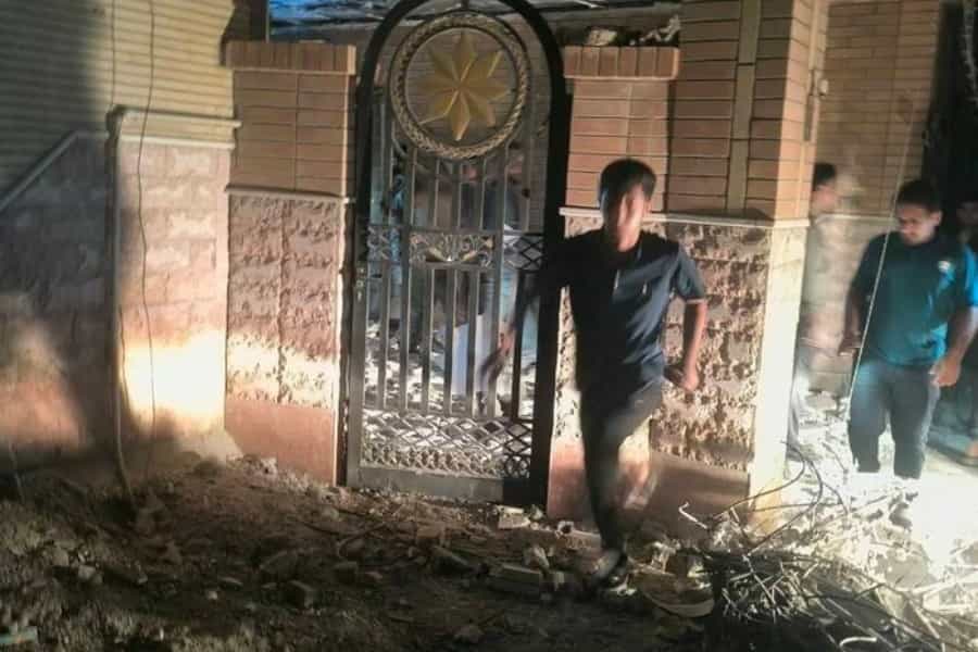 چند نفر در تاریکی شب در کنار ساختمانی ویرانشده در حال دویدن هستند.