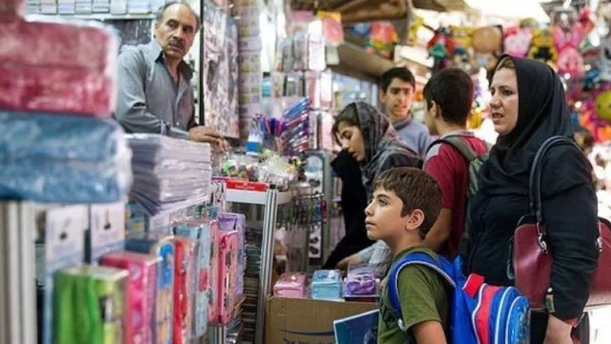 چند نفر و یک فرزند در کنار مغازه لوازم مدرسه
