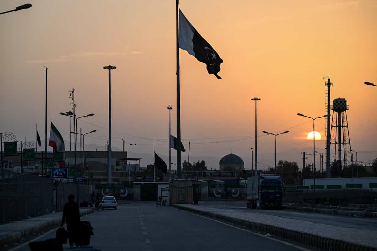 رچم ملی ایران (چپ) در حالی که نیمهافراشته است، همزمان با به اهتزاز درآمدن پرچم پاکستان (وسط) هنگام غروب آفتاب در گذرگاه مرزی ایران و پاکستان در تفتان، ایالت بلوچستان، در ۴ مارس ۲۰۲۶ دیده میشود. شهروندان پاکستانی در حالی که چمدانهای خود را از مرز ایران عبور میدادند، از شلیک موشکها و آشفتگی در رفتوآمدها سخن گفتند؛ آنها برای خروج از ایران، پس از حملات آخر هفته ایالات متحده و اسرائیل به این کشور، تلاش میکردند.