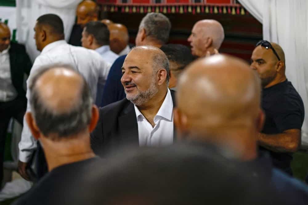 در تصویر عدهای منصور عباس، رهبر حزب عربی-اسرائیلی «رعام» را احاطه کردهاند و او در گفتوگو با افراد لبخند میزند.