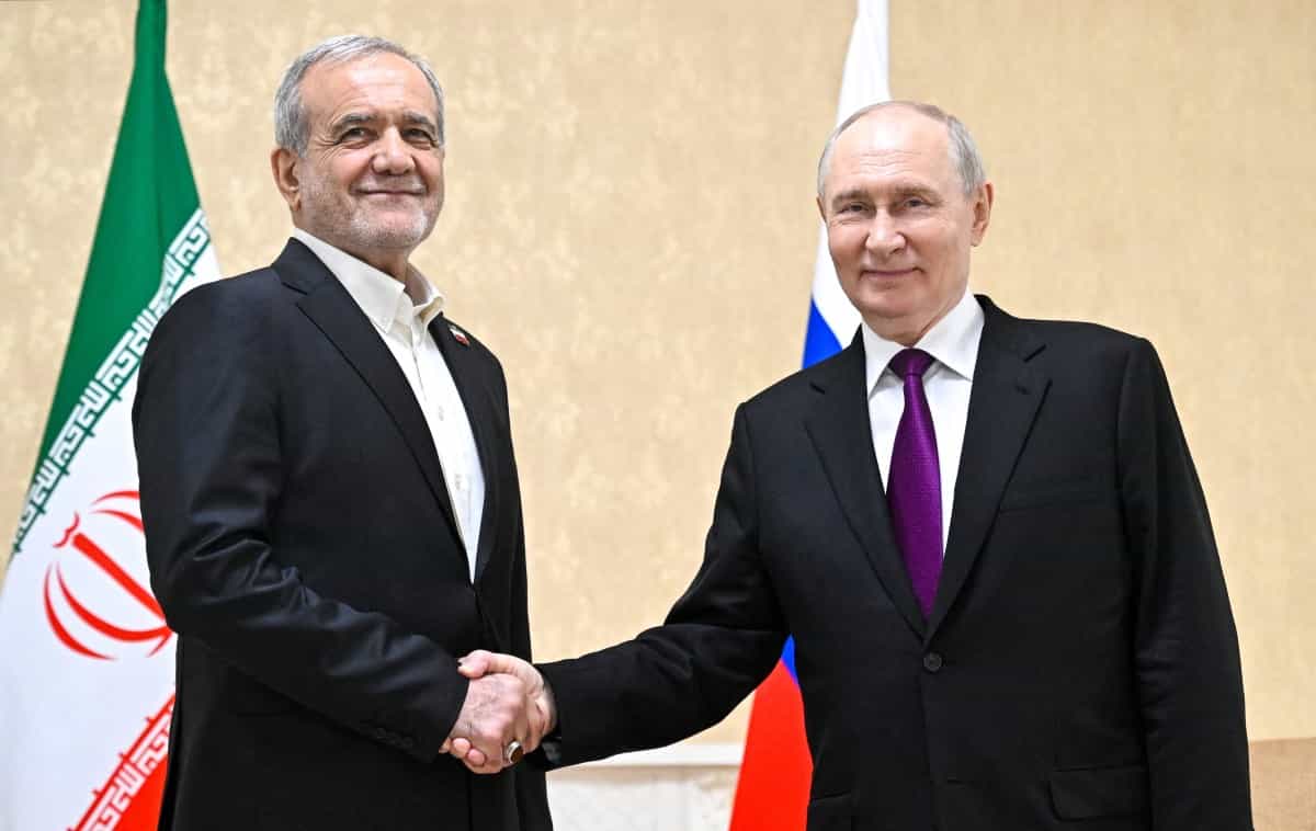 مسعود پزشکیان و ولادیمیر پوتین دست یکدیگر را فشردهاند و میخندند.