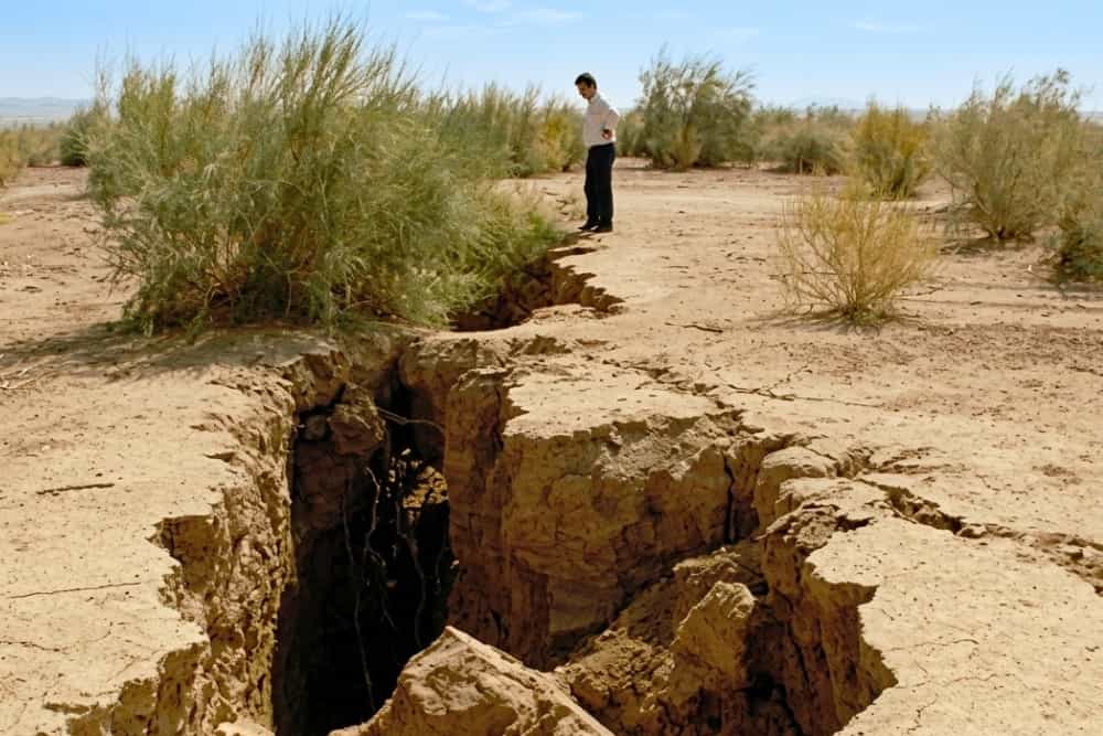 تصویری از خاک فرونشسته و فرسوده شده و یک مرد در کنار آن